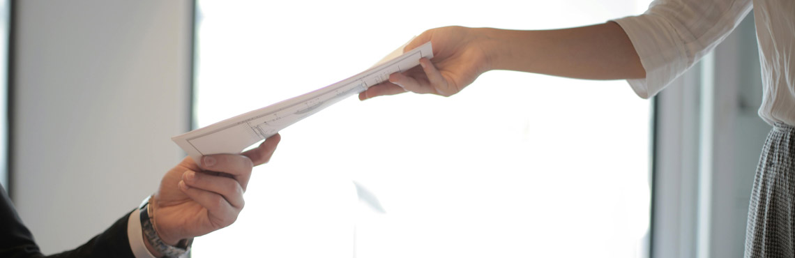 A woman passes a document to a man.